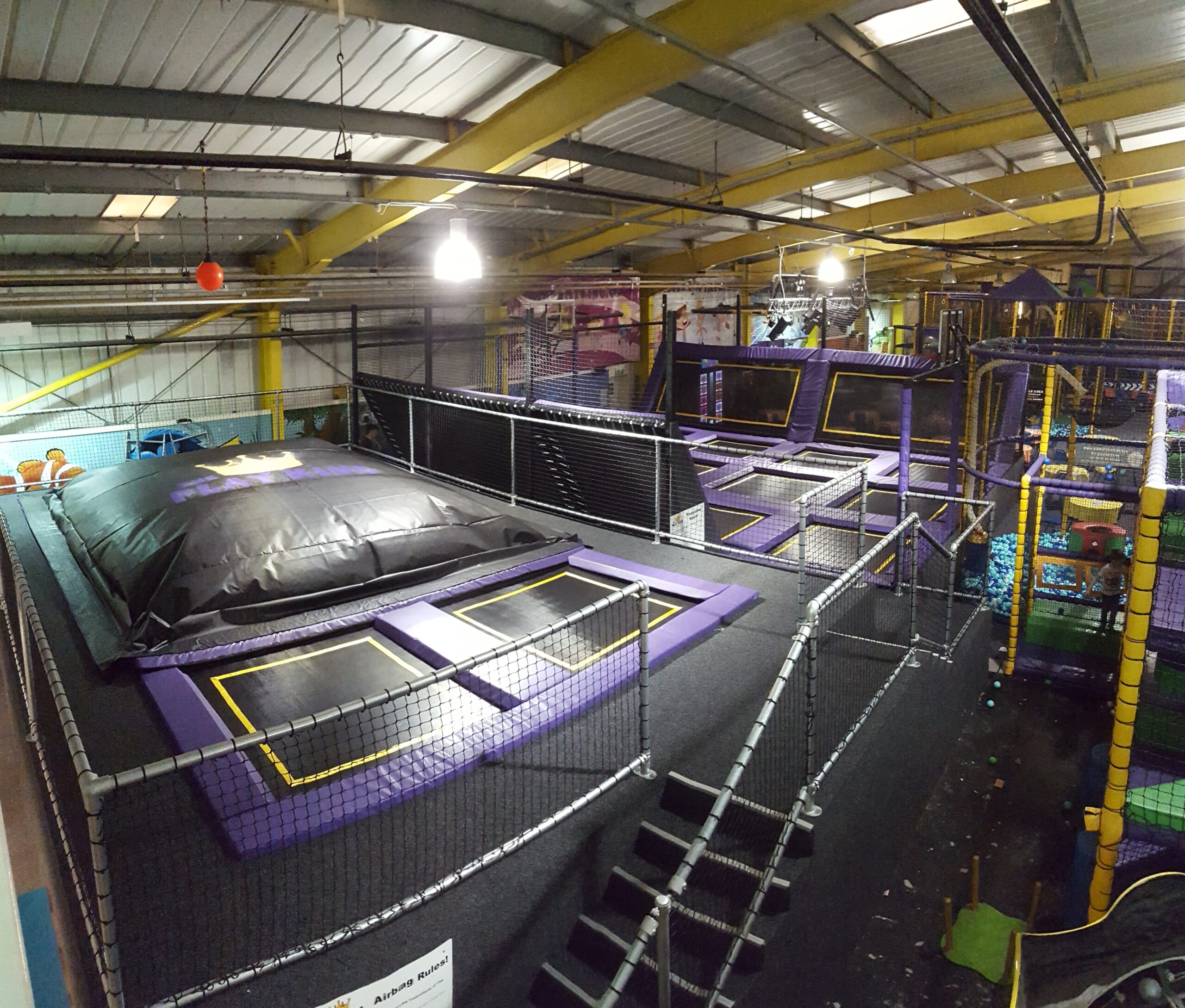 A large indoor trampoline park, featuring a range of trampolines and an air bag.