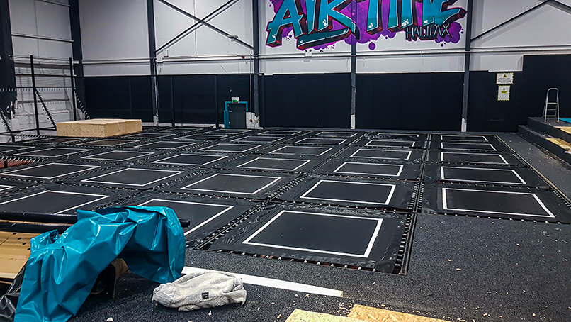 The process of fitting trampolines into the floor of an indoor trampoline park.