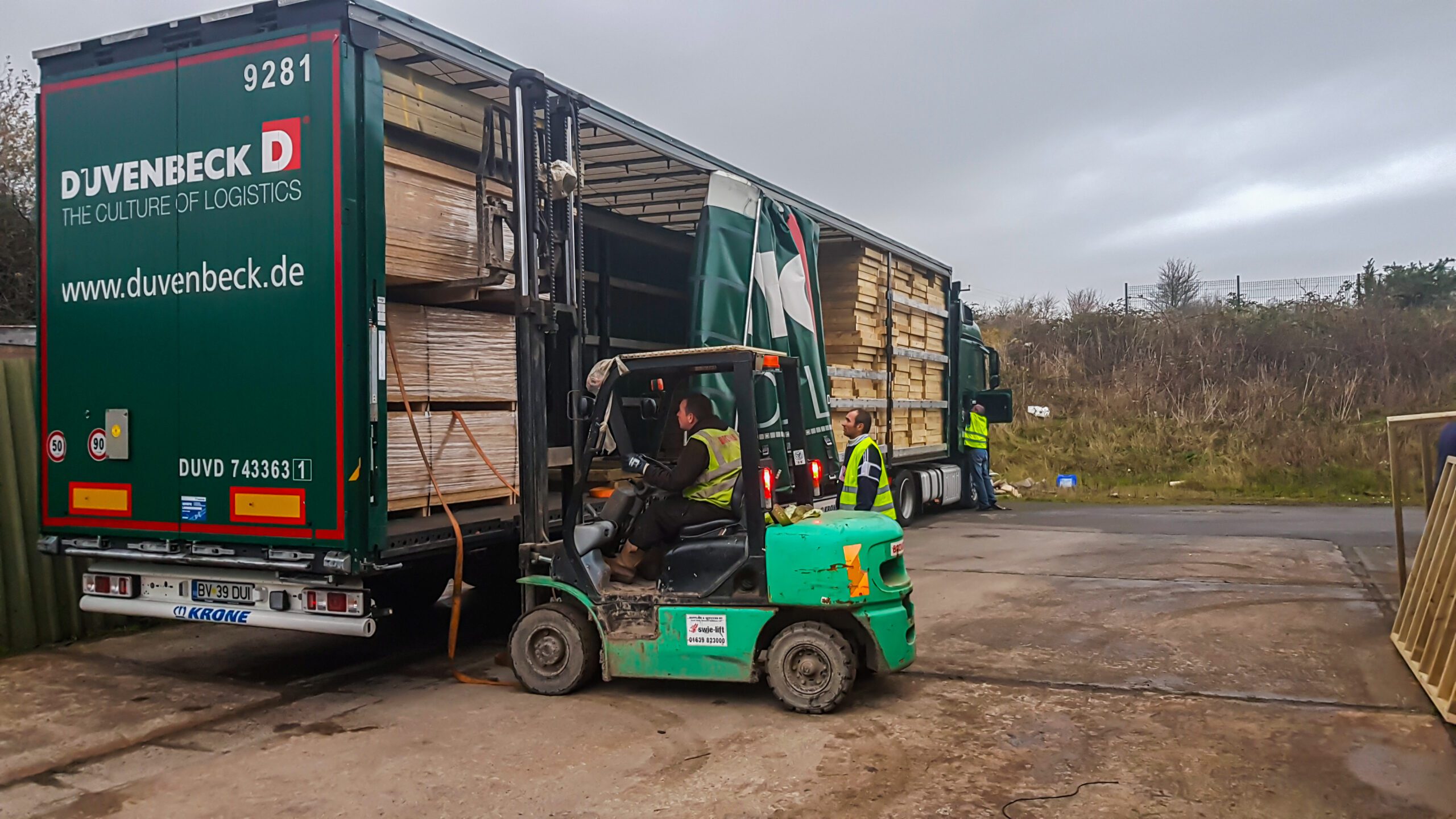 A forklift lifting materials off a lorry container