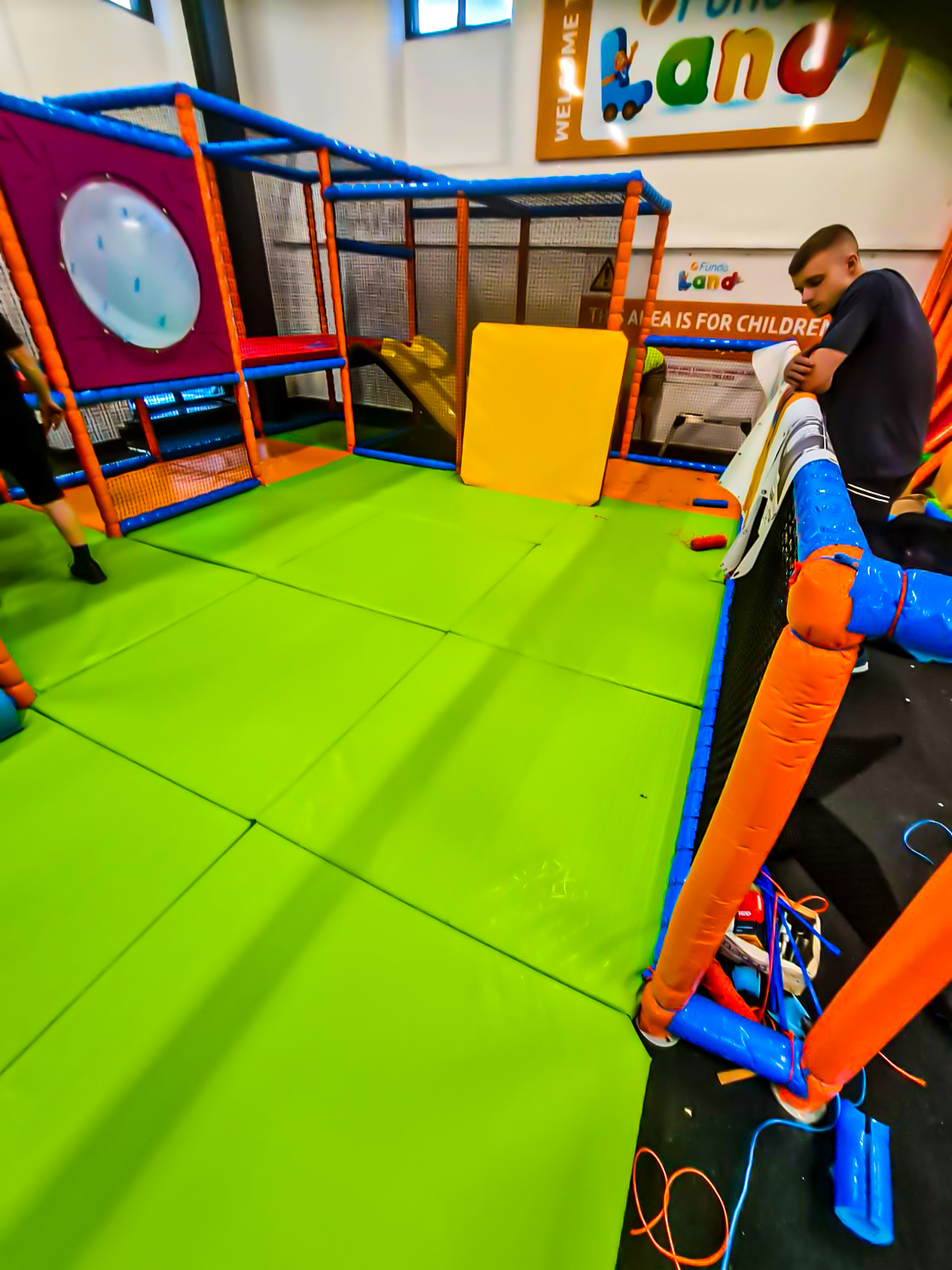 Bright green mats added to a play area and someone providing maintenance