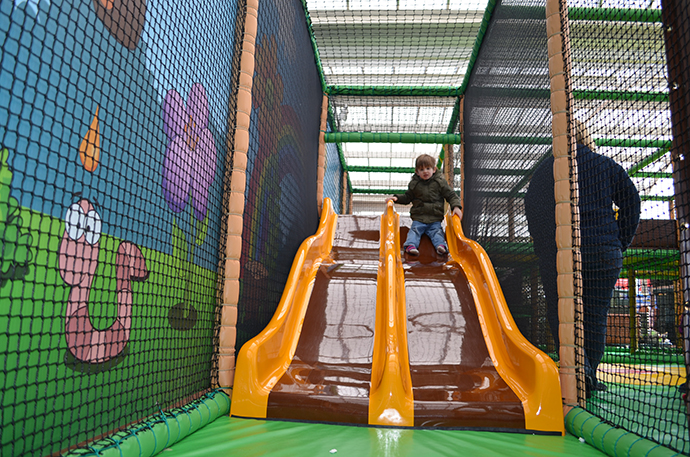 A child sliding down a play area slide.