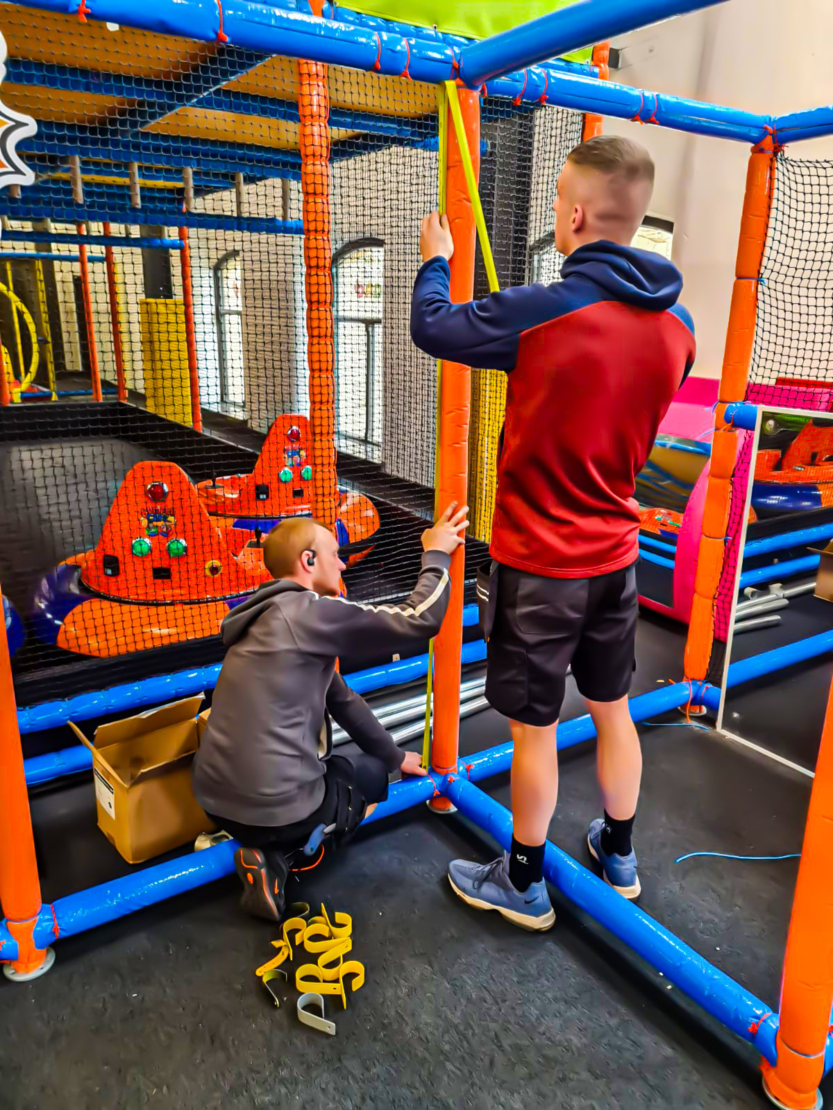 Two workers maintaining an indoor play area, ensuring everything is safe and fun for kids to enjoy.